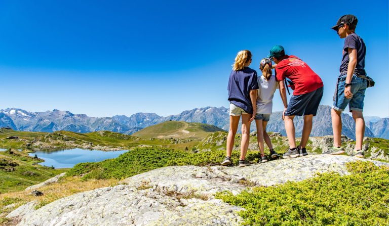 Famille de 4 personnes regardant au loin la montagne et son lac